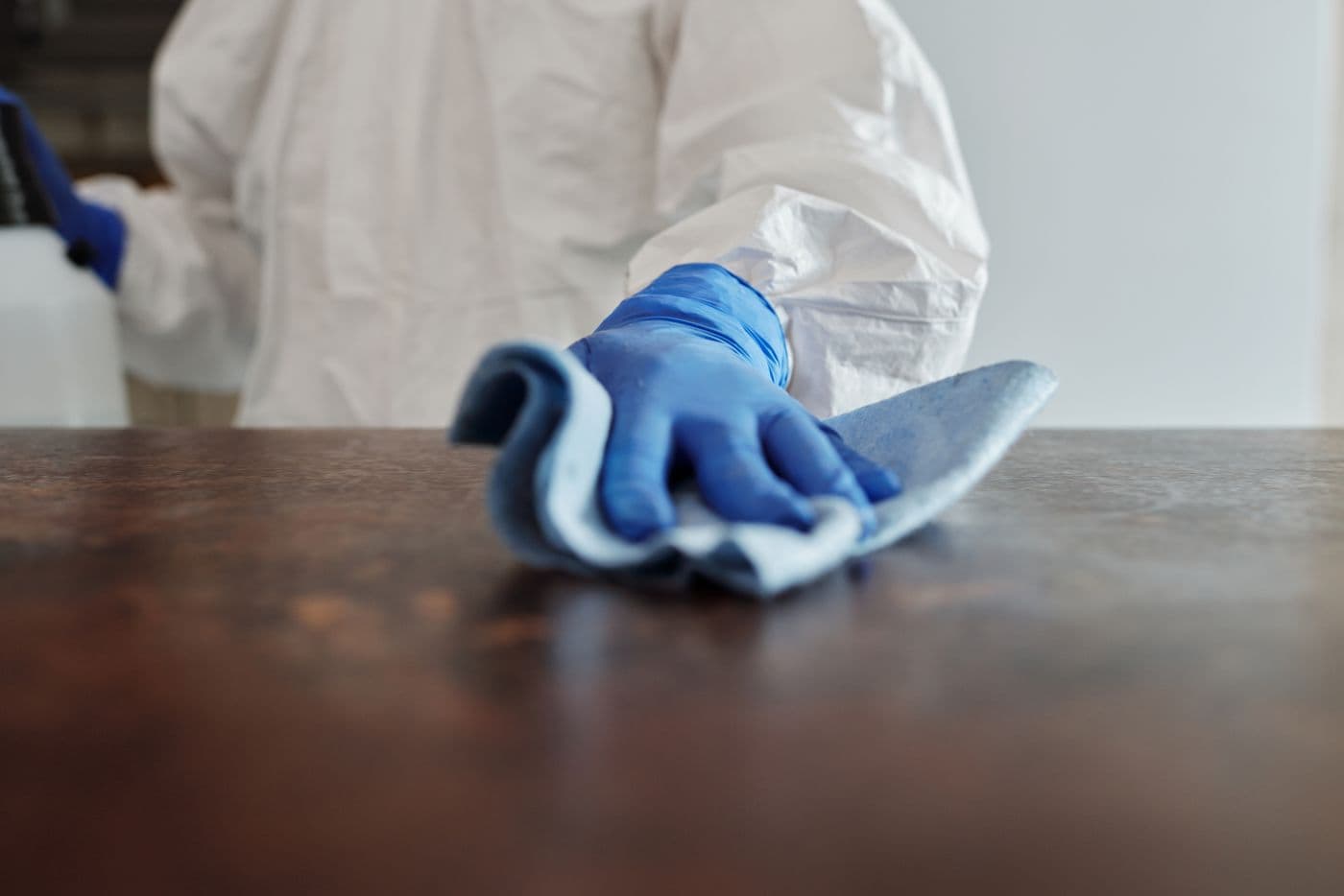Essuyage d'un comptoir avec gants et lavette, tenue de travail blanche