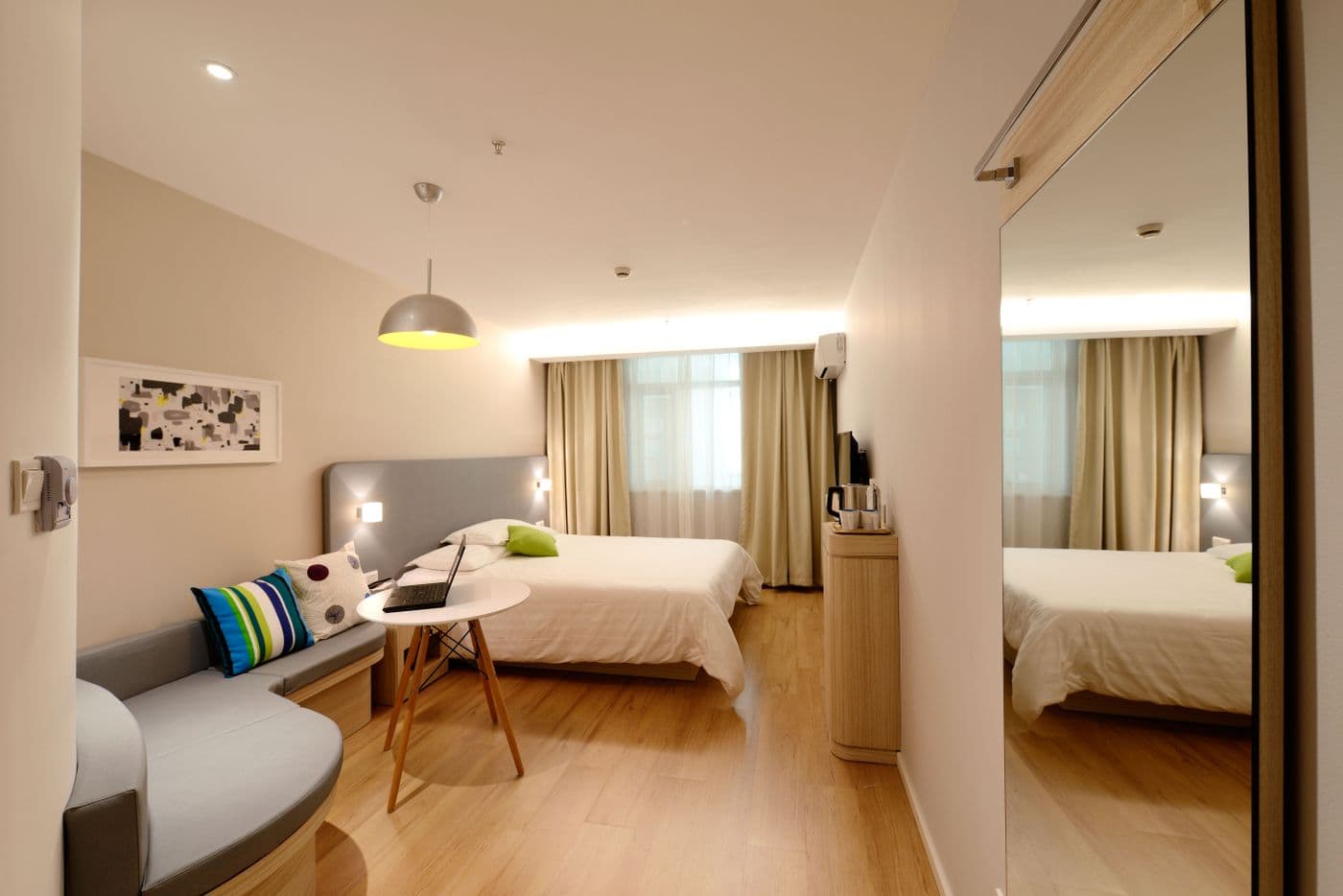 Chambre d'hôtel claire au lit fait, parquet et miroir impeccables